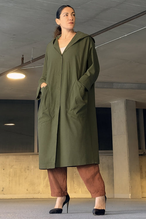 Oversized water-resistant green windbreaker jacket with hood and large pockets, waterproof design.