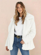 Woman wearing white open front oversized faux fur jacket with draped shawl collar and mid-hip length over casual outfit
