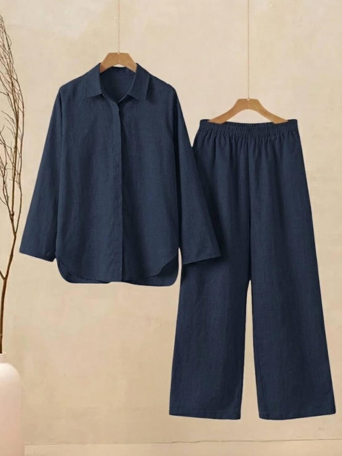 Oversized 100% cotton navy shirt and wide-leg pants co-ord set hanging on wooden hangers against beige wall