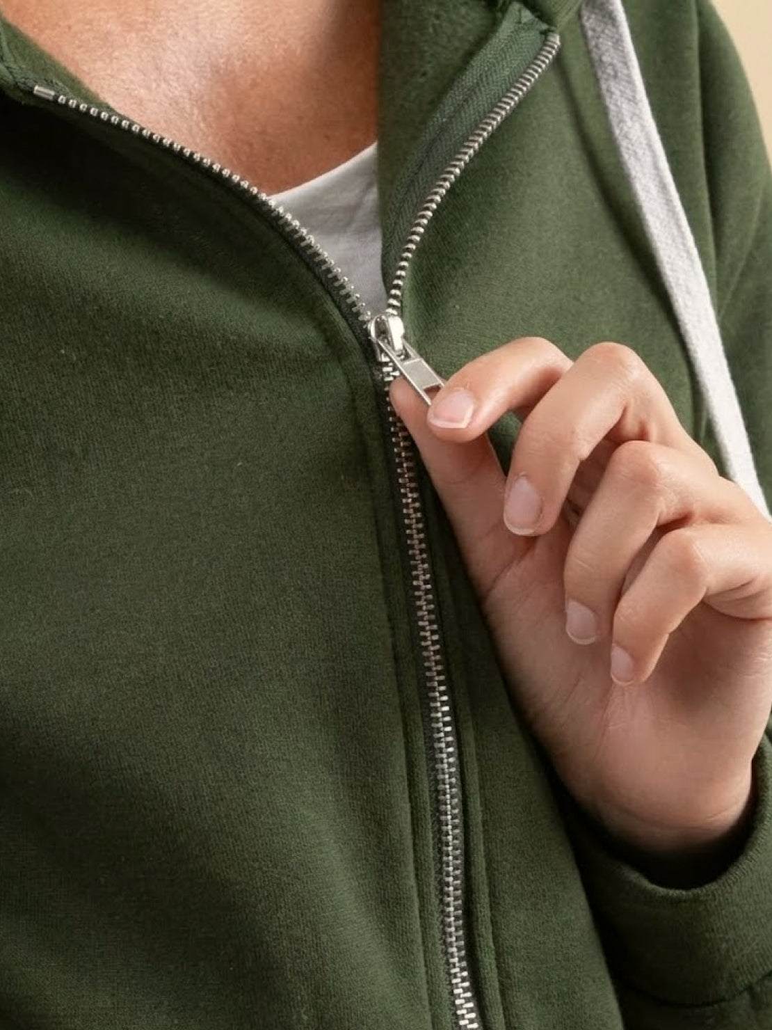 Close-up of hand zipping up oversized long zip sweatshirt hoodie in olive green fleece material