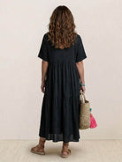 Woman wearing a V-neck two-tiered maxi swing dress in flowy cotton fabric with irregular hemline and draped sleeves