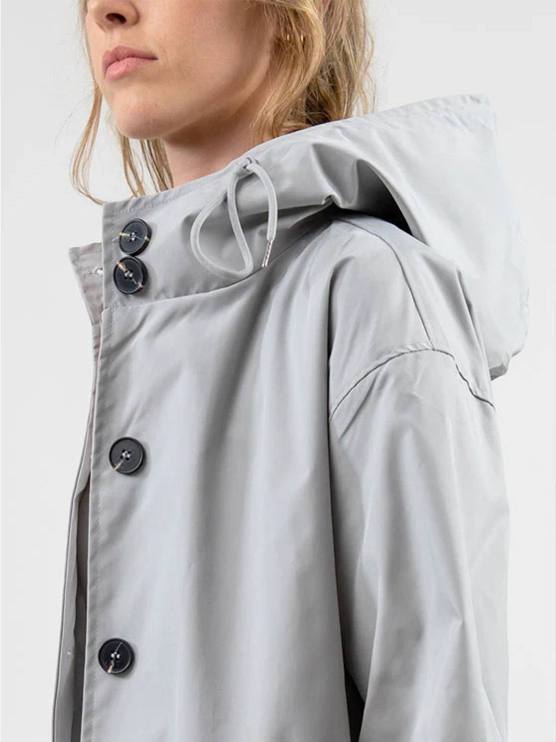 Water-resistant oversized hooded windbreaker rain jacket with multiple pockets and adjustable waist.